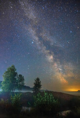 breathtaking Milky Way galaxy stretching across a dark night sky above a misty, peaceful rural landscape © Александр Арендарь