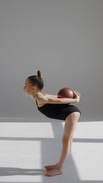 Little gymnast posing with a ball on a white background. 