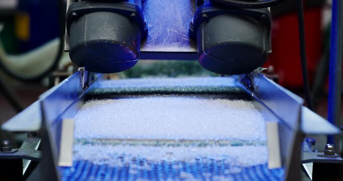 Industrial machine with two round motor components vibrating to process white plastic pellets