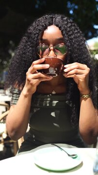 Young woman drinking and enjoying coffee in a cafe outdoors