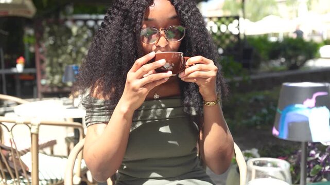 Young woman drinking and enjoying coffee in a cafe outdoors