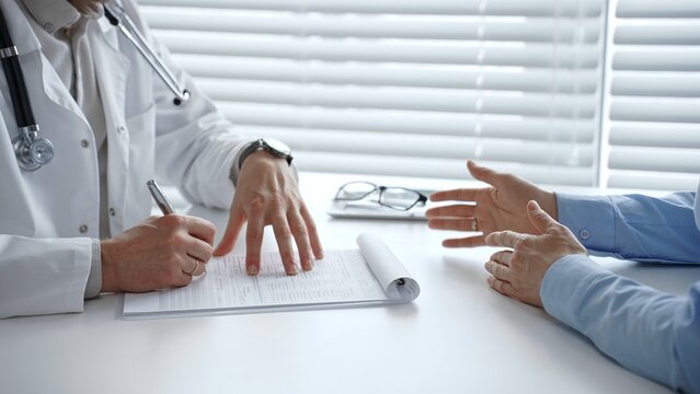 Doctor and patient discussing diagnosis, treatment options, and healthcare plan during a medical consultation in clinic, focusing on communication and shared decision making