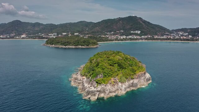 Koh Pu in Kata Bay with Kata Noi beach and lush Phuket hills in background, tropical travel destination with clear blue turquoise water. Thailand's natural landscape. Aerial view drone flight panorama
