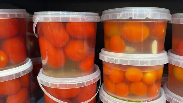 Tomato containers stacked on store shelf display fresh produce in plastic packaging background