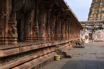 Obraz premium Intricately carved stone pillars lining the courtyard of Virupaksha Temple in Hampi, Karnataka, India, showcasing the architectural brilliance and sculptural artistry of the Vijayanagara Empire