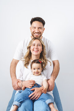 A cheerful young family with a happy, baby in photo studio. The parents are smiling.