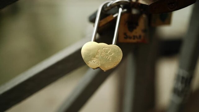 Golden heart love lock secured on a metal railing with other padlocks