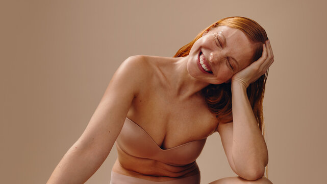 Smiling woman relaxed with hand supporting head in nude tones