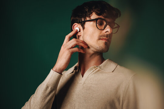 Streaming keeps man engaged with earbuds in a studio portrait