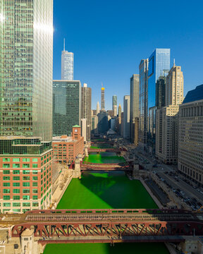 Aerial view of the Chicago River dyed bright green, flowing through downtown skyscrapers and historic bridges in Chicago, Illinois, United States.