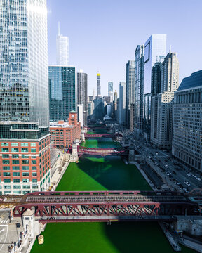 Aerial view of the Chicago River dyed green for St. Patrick's Day, flowing through the downtown skyline with historic bridges and modern skyscrapers in Chicago, Illinois, United States.
