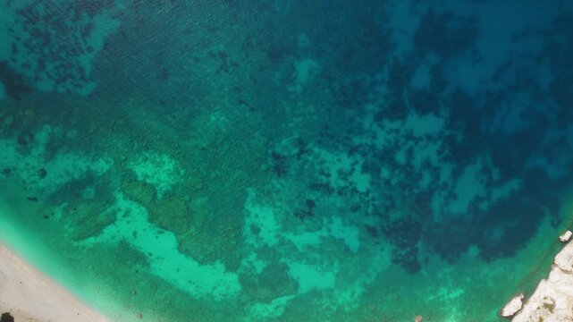 Top view of deep blue sea with coral reef patterns near coastal shore in Greece