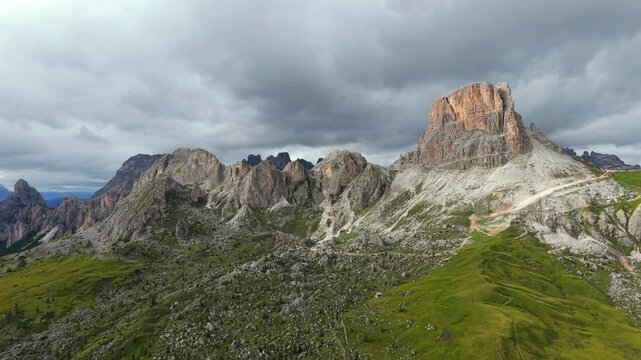 Stunning aerial view of Passo Giau and the majestic Ra Gusela peak in the Dolomites. The dramatic mountain landscape under a cloudy sky