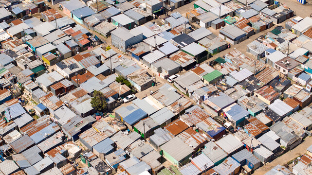 Aerial view of a dense informal settlement with corrugated metal rooftops and narrow alleyways in Cape Town, Western Cape, South Africa.