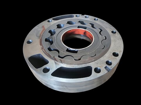 Assembled metallic gerotor internal gear set inside its circular flange housing for automotive transmission oil pump isolated on black background.