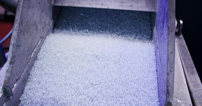 Granulated white material moving across a perforated metal screen on an industrial production line