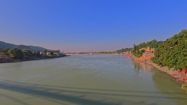 Wide-angle view of the Ganges River looking downstream from Ram Jhula towards Janki Jhula in Rishikesh, India.