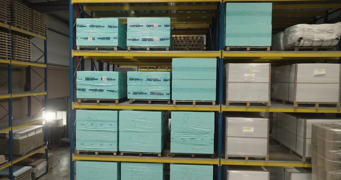 Warehouse storage racks filled with stacked pallets containing wrapped boxes and materials