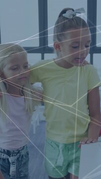 Vertical video: Two girls arm-in-arm by window, reacting to animated network and smiling for school