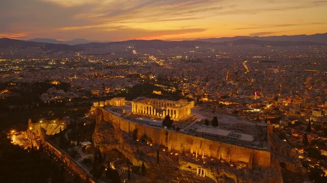 Majestic aerial view of the illuminated acropolis of athens, with the historic parthenon temple glowing against the backdrop of the sprawling city skyline during a beautiful twilight sunset