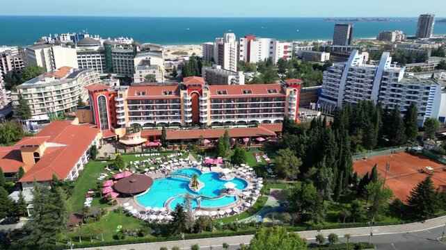 Drone passes a hotel with a pool in Sunny Beach while the beach and Black Sea coastline stretch across the background in Bulgaria.