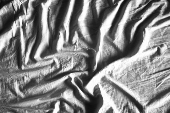 Wrinkled white fabric texture with dramatic shadows. High contrast black and white bed sheet overlay for photo editing, backgrounds, and displacement maps. Transparent PNG