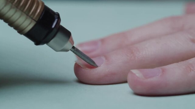 Professional electric nail drill filing cuticle of female hand in beauty salon, closeup hardware manicure care process, 4K video of hygienic treatment cosmetic procedure, dermatology