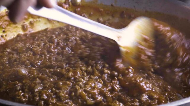 Extreme close up of stirring bolognese sauce in pan