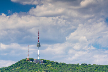 Obraz premium N Seoul Tower on top of Namsan Mountain against beautiful blue sky with fluffy white clouds in Seoul, South Korea