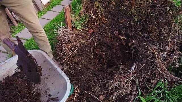 A gardener turns a compost pile with a pitchfork to enrich nutrients and aerate the soil