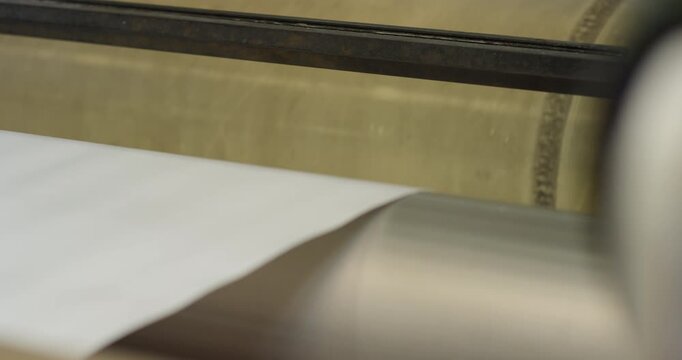 A sheet of white paper being fed into a heavy industrial machine