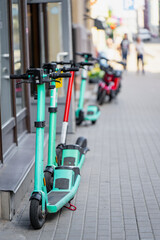 Row of shared electric scooters parked on a paved urban sidewalk representing modern micromobility, green city transportation, and eco friendly commuting © K