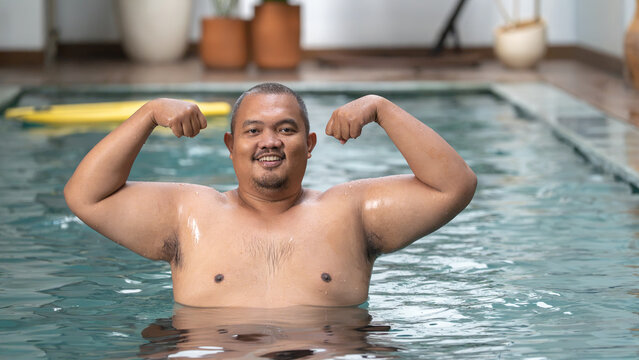 Happy Overweight Asian Man Flexing Muscles in Swimming Pool, Body Positive Fitness Concept