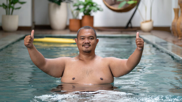 Happy Overweight Asian Man Giving Two Thumbs Up in Swimming Pool, Body Positive Concept