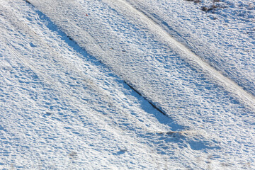 Fototapeta premium Snow blankets a field, showing deep tire tracks