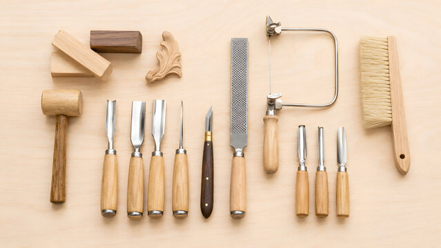 Assorted woodworking hand tools arranged on light wooden table