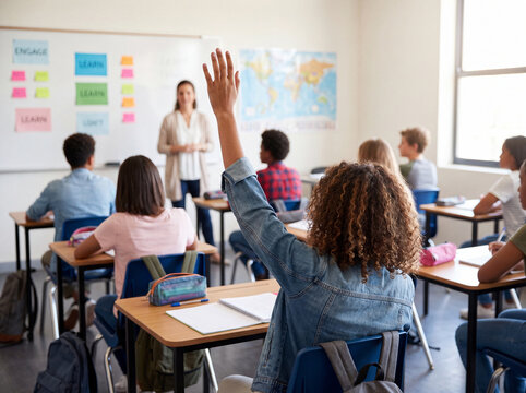 Student raising hand to ask question in high school classroom lesson with teacher