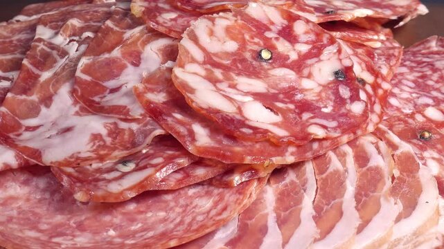 meat platter rotating with assortment of various spanish, french or italian appetizers - sliced prosciutto, parma sausage, ham, boiled pork, salami, close up