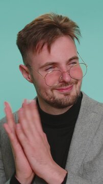 Sneaky cunning business man with tricky face gesticulating and scheming evil plan, thinking over devious villain idea, cunning cheats, jokes and pranks. Young boy on blue studio background indoors