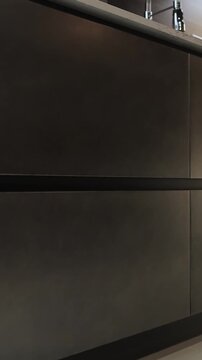 Vertical video. Dark metal kitchen cabinetry with minimalist design and modern interior details.