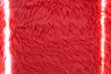 Vivid red faux fur texture close-up. Close-up of vivid red faux fur with dense shaggy fibers, soft plush texture, and narrow vertical white light gaps across the frame. © Iryna