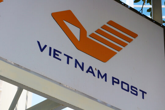 NHA TRANG, VIETNAM - JANUARY 26, 2026: A close-up view of the orange corporate logo and dark blue text sign of Vietnam Post displayed on a white wall.