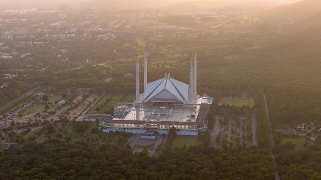 Aerial view of Faisal Mosque surrounded by lush greenery and the Margalla Hills in Islamabad, Pakistan.