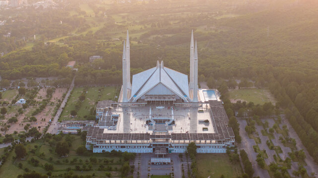 Aerial view of Faisal Mosque with its iconic tent-shaped prayer hall and four slender minarets surrounded by lush greenery and gardens, Islamabad, Pakistan.