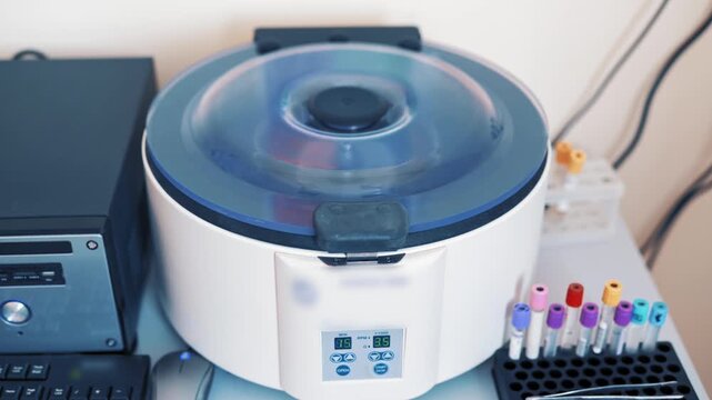 Medical centrifuge for blood plasma in motion, spinning vials containing blood samples for analysis.