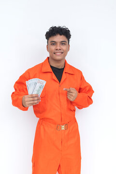 Young Filipino seafarer in orange coveralls proudly displays a stack of dollar bills while smiling, representing income, success, and maritime employment.