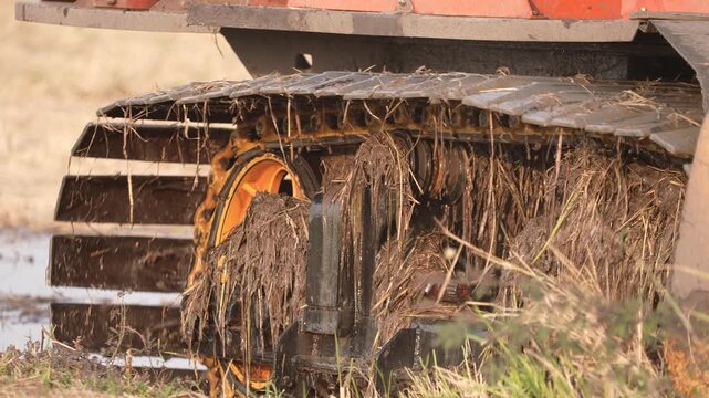 Muddy track wheel agriculture harvest machine field soil grass rural farmland vehicle heavy machinery rubber tread stuck in wet ground with straw debris and outdoor texture