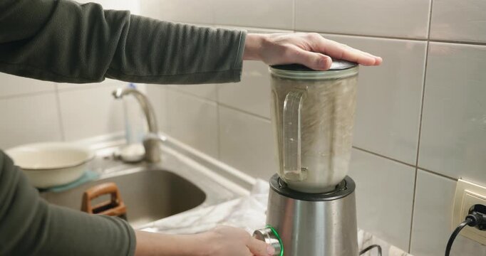 Caucasian man makes sauce mixing in blender. Single male is cooking at kitchen at home. 4K 10-bit
