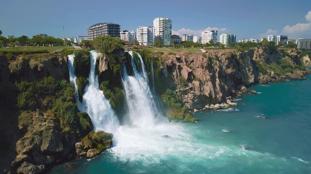 Beautiful drone shot of the famous Duden waterfall cascading from city cliffs into blue sea water in Turkey