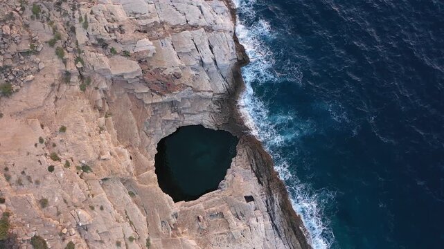 Aerial slow motion view of Giola natural pool near the Mediterranean seaside. Waves crushing the shoreline. Thassos island, Greece